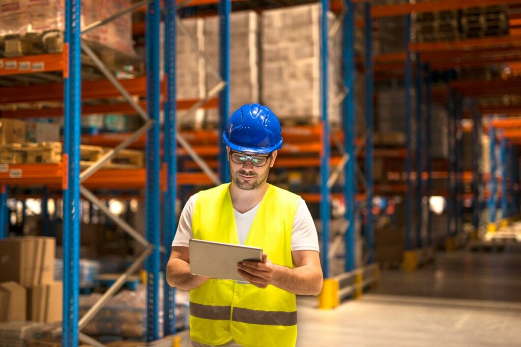 homem fazendo leitura de um tablet dentro de um depósito