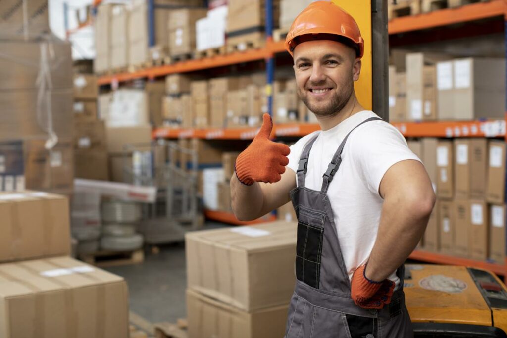 homem sorrindo dentro de um deposito com varias caixas.