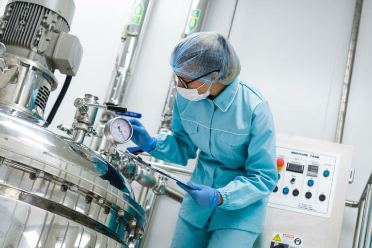 cientista dobrado em uniforme de laboratório azul verifica como o tanque do compressor funciona tablet nas mãos perto