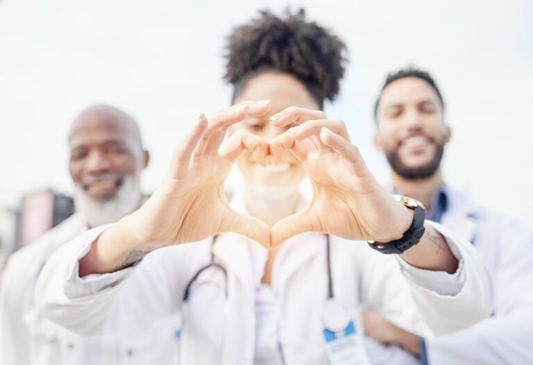 trabalhadores hospitalares sorrindo fazendo coração com a mão.